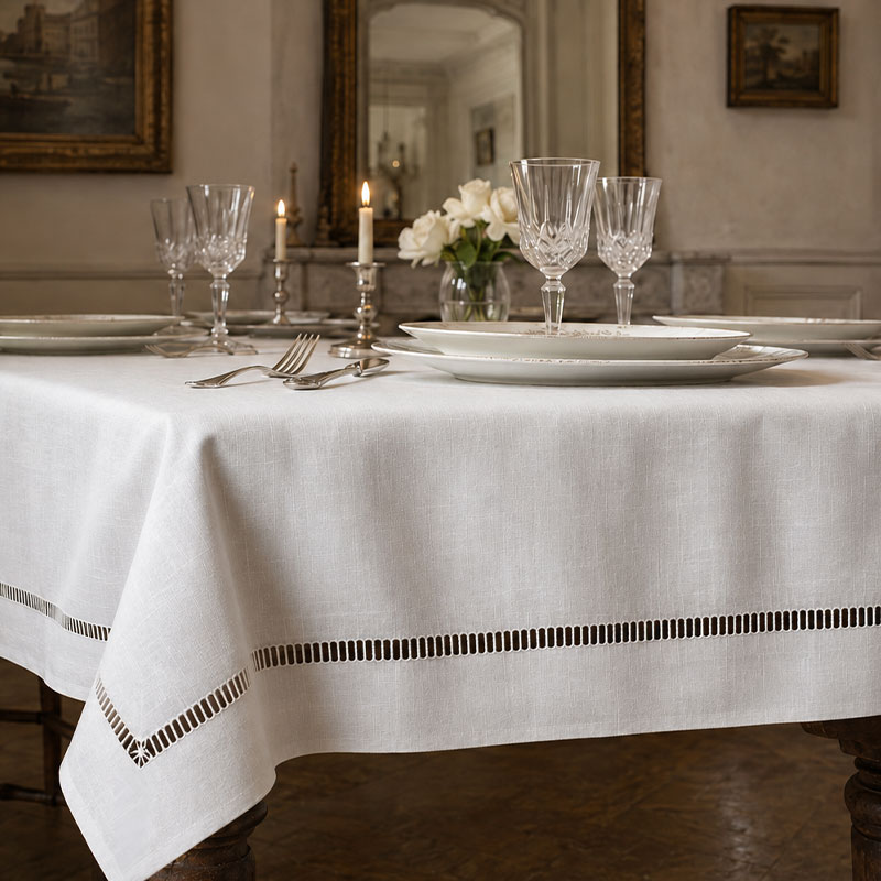 luxury-linen-tablecloth-bastoncino-la-bottega-di-casa Tovaglia in lino bianco con sfilato a bastoncino su tavolo apparecchiato in interno classico con specchi dorati, cristalli, candele e rose bianche