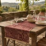 Runner jacquard Optical bordeaux con frange su tavolo rustico apparecchiato all’aperto